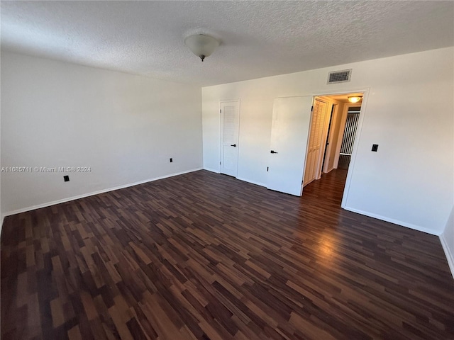 spare room featuring dark wood-type flooring and a textured ceiling