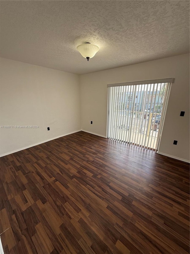 unfurnished room featuring a textured ceiling and dark hardwood / wood-style flooring