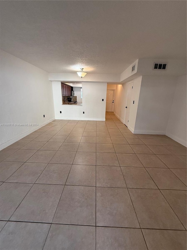 unfurnished living room featuring a textured ceiling and light tile patterned floors