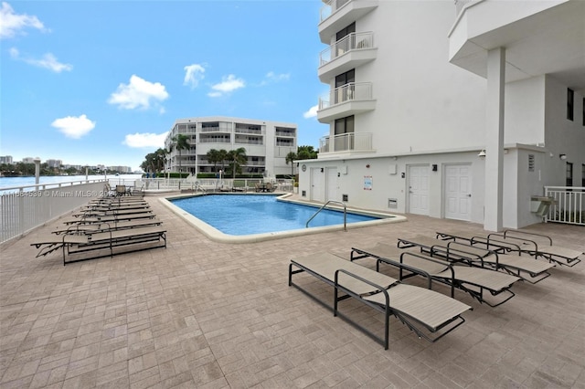 view of swimming pool featuring a patio and a water view