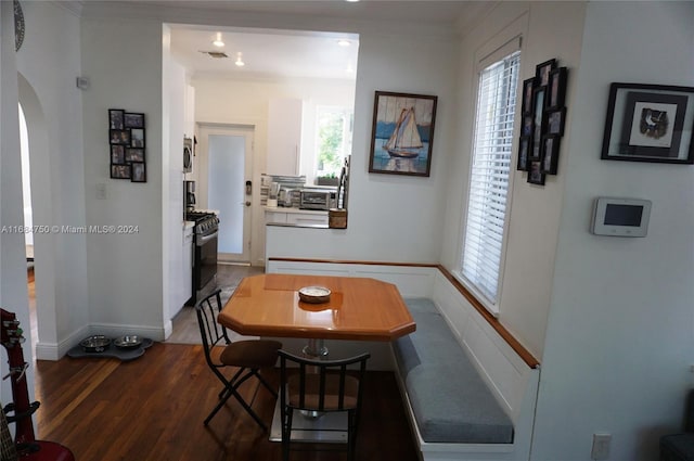 dining area featuring dark hardwood / wood-style flooring, crown molding, and a wealth of natural light