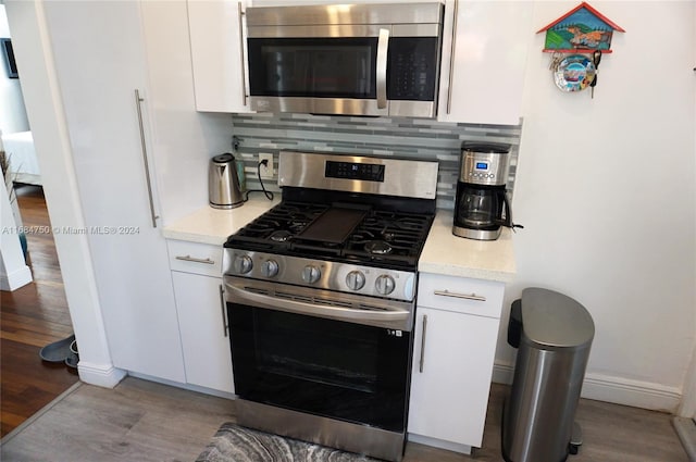 kitchen with appliances with stainless steel finishes, light hardwood / wood-style flooring, and white cabinets