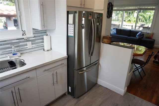 kitchen with backsplash, white cabinetry, light hardwood / wood-style floors, and stainless steel refrigerator