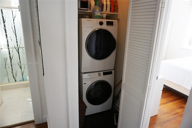 washroom with stacked washing maching and dryer and hardwood / wood-style floors