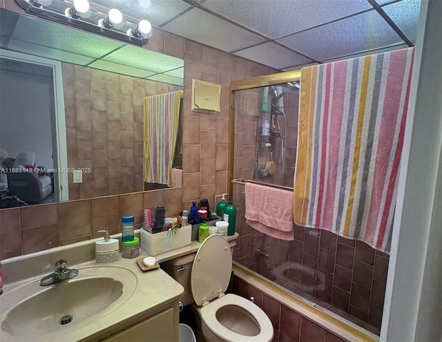 full bathroom featuring a paneled ceiling, toilet, vanity, and combined bath / shower with glass door