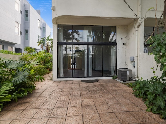 doorway to property with central AC and stucco siding