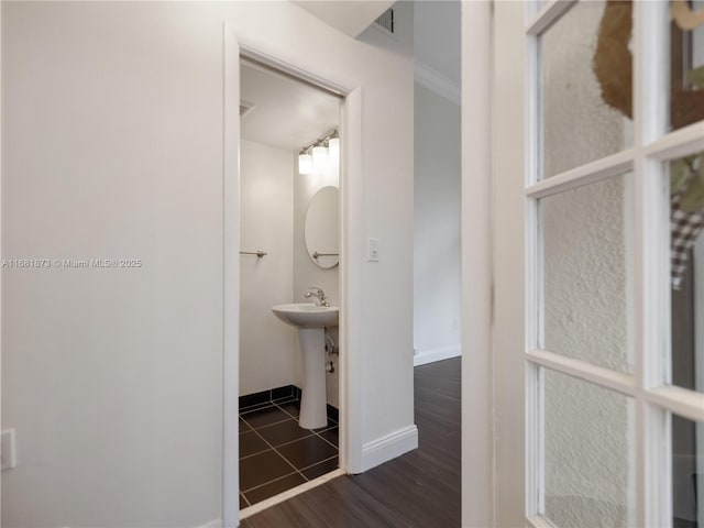 corridor with baseboards, dark wood-style floors, and a sink