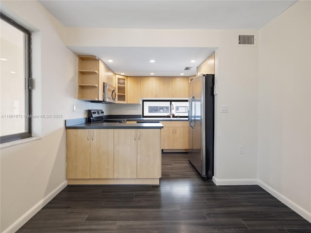 kitchen with dark wood-type flooring, appliances with stainless steel finishes, light brown cabinetry, and kitchen peninsula