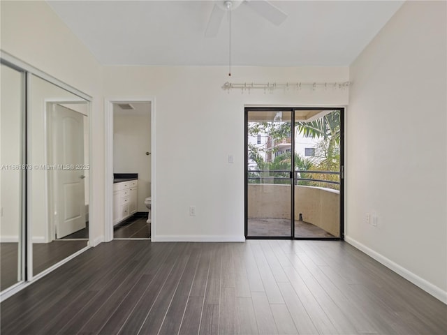 unfurnished bedroom featuring access to outside, dark wood finished floors, baseboards, connected bathroom, and ceiling fan