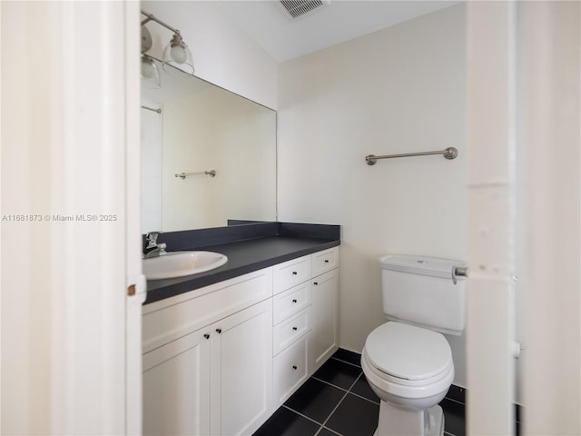 bathroom with toilet, vanity, and tile patterned floors