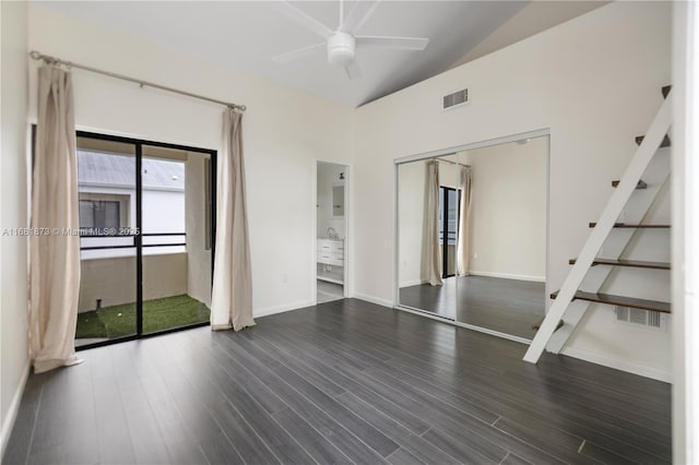 unfurnished room with ceiling fan, baseboards, dark wood-type flooring, stairway, and lofted ceiling