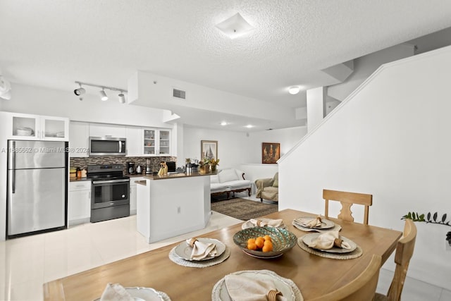 tiled dining room featuring a textured ceiling and rail lighting