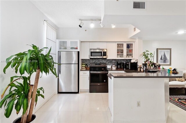 kitchen featuring white cabinetry, stainless steel appliances, light tile patterned floors, and backsplash