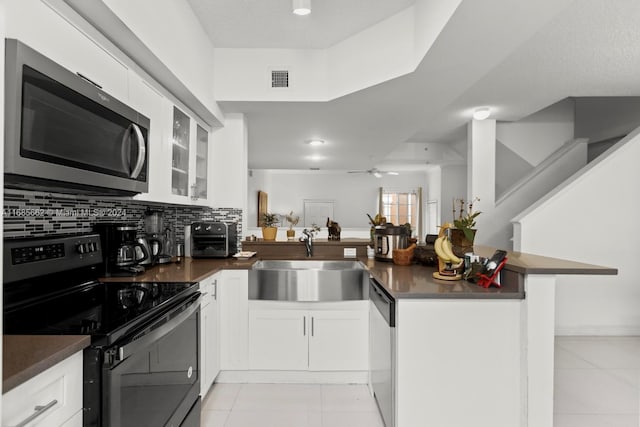 kitchen with sink, appliances with stainless steel finishes, kitchen peninsula, and white cabinets