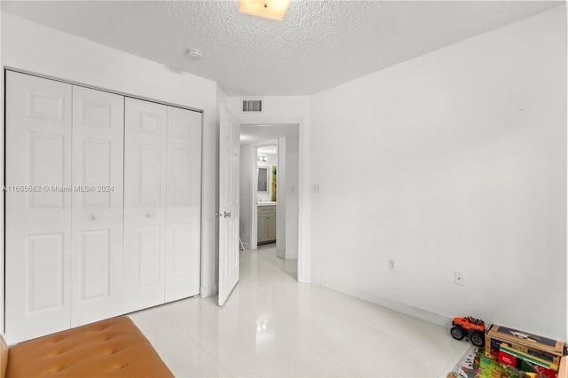 tiled bedroom featuring a closet and a textured ceiling