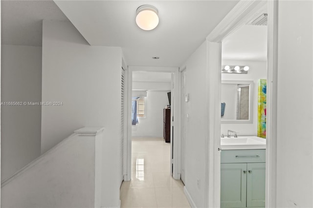 corridor with sink, light tile patterned floors, and plenty of natural light