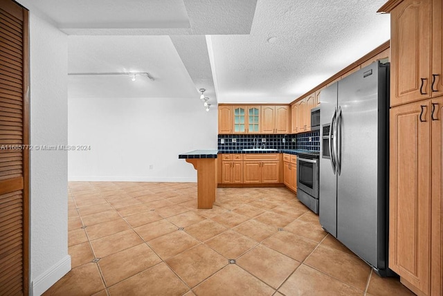 kitchen with tasteful backsplash, a kitchen bar, a textured ceiling, stainless steel appliances, and light tile patterned floors