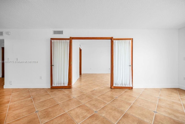 tiled empty room with a textured ceiling