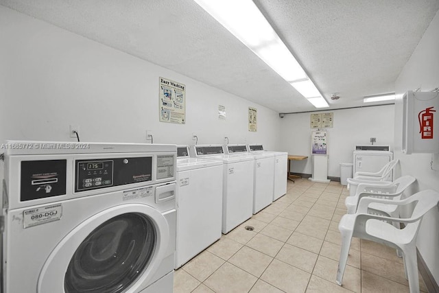 clothes washing area featuring a textured ceiling, washing machine and dryer, and light tile patterned floors