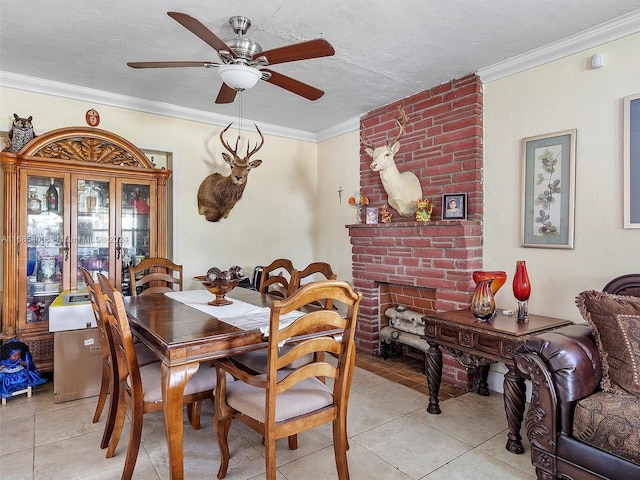 dining area featuring ceiling fan, light tile patterned floors, a textured ceiling, a fireplace, and crown molding