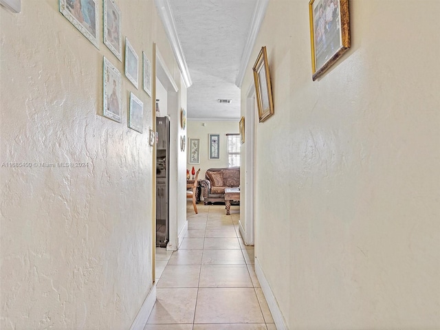 corridor featuring crown molding, a textured ceiling, and light tile patterned floors