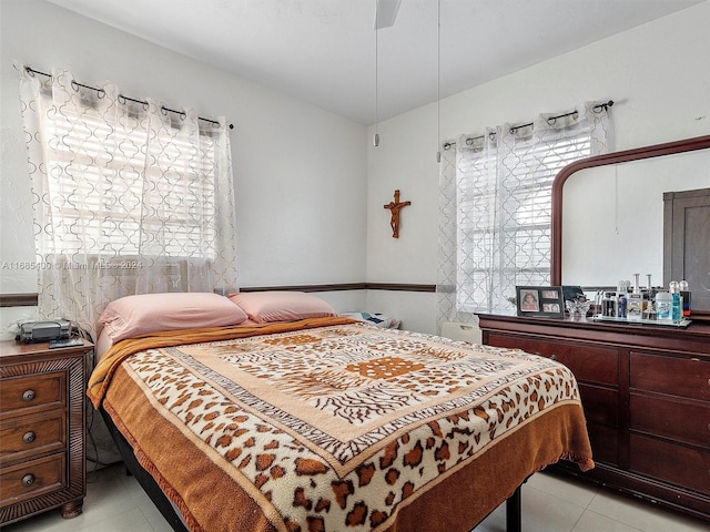 bedroom with multiple windows, light tile patterned floors, and ceiling fan