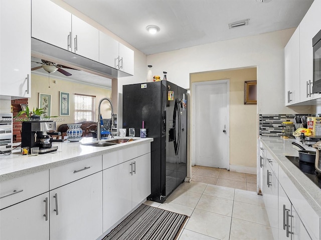 kitchen with sink, white cabinets, light tile patterned flooring, and black appliances