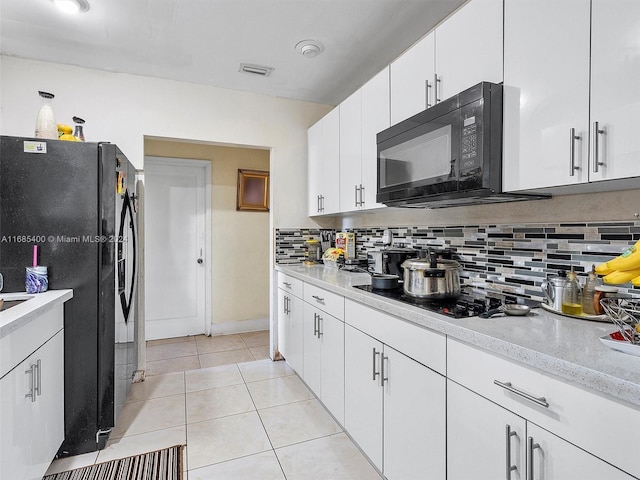 kitchen featuring tasteful backsplash, black appliances, light tile patterned flooring, and white cabinets