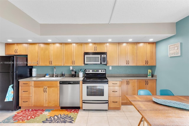 kitchen with light brown cabinets, appliances with stainless steel finishes, light tile patterned floors, and sink