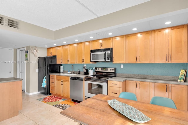 kitchen with light brown cabinets, appliances with stainless steel finishes, and light tile patterned flooring