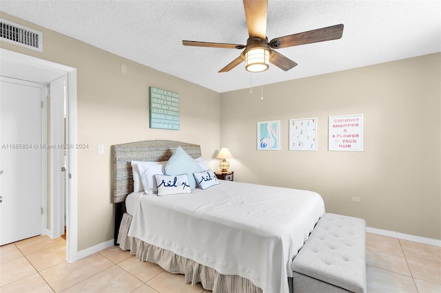 tiled bedroom with ceiling fan and a textured ceiling