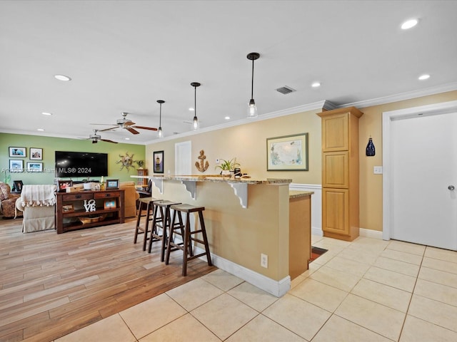 kitchen featuring light hardwood / wood-style floors, a center island, light stone counters, and hanging light fixtures