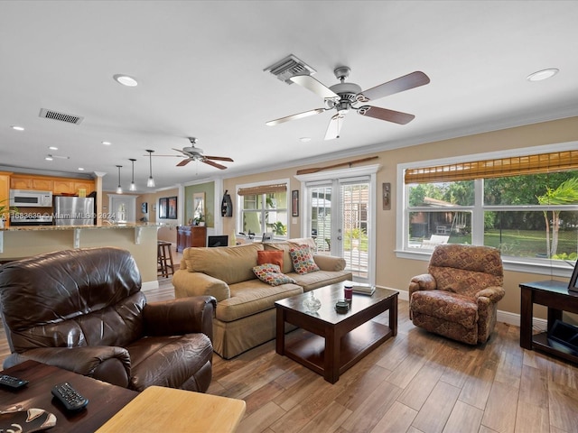 living room featuring crown molding, light hardwood / wood-style flooring, and plenty of natural light