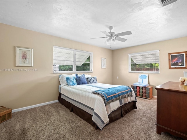 bedroom with ceiling fan, multiple windows, and carpet flooring