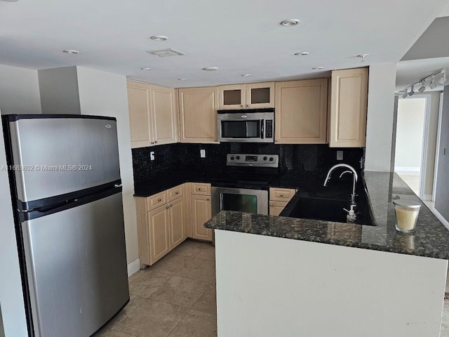 kitchen with sink, kitchen peninsula, stainless steel appliances, dark stone countertops, and light brown cabinets