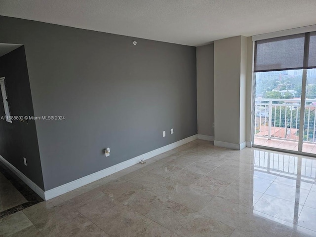 empty room with a textured ceiling and light tile patterned floors