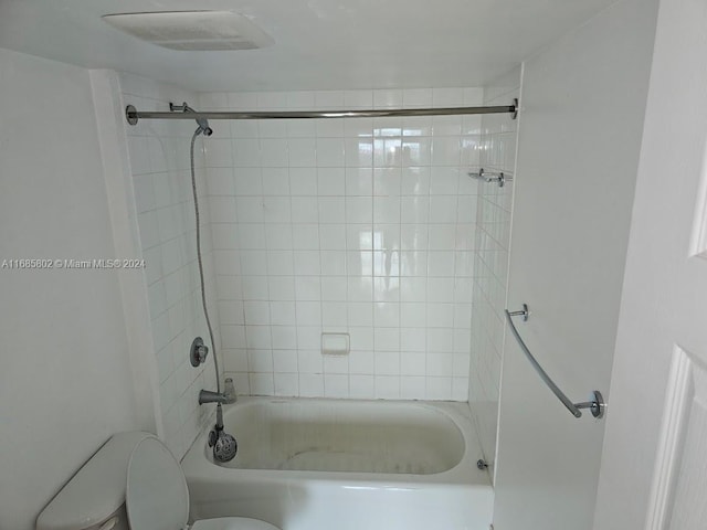 bathroom with tiled shower / bath combo and toilet