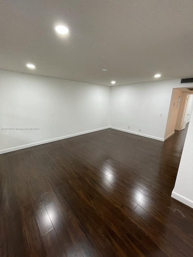 spare room with a textured ceiling and dark hardwood / wood-style floors