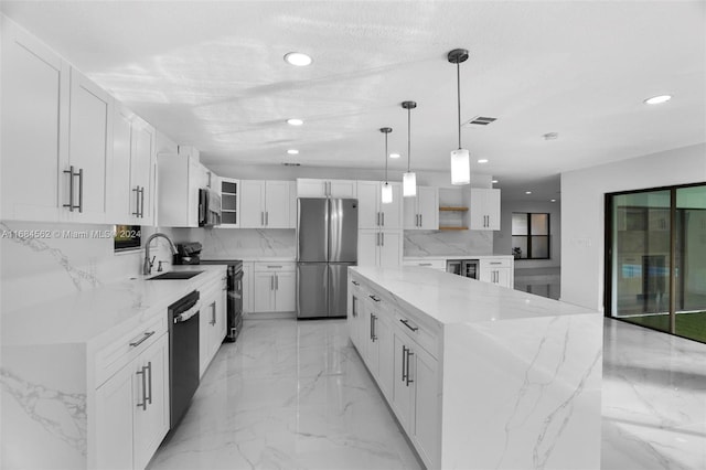 kitchen featuring sink, black appliances, pendant lighting, white cabinetry, and light stone counters