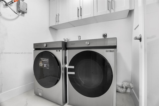 laundry room featuring washer and clothes dryer and cabinets