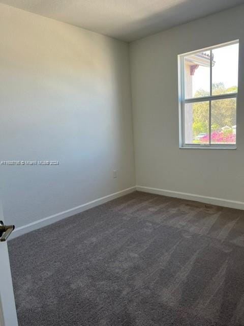 spare room featuring dark colored carpet