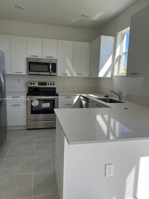 kitchen featuring kitchen peninsula, white cabinets, and stainless steel appliances