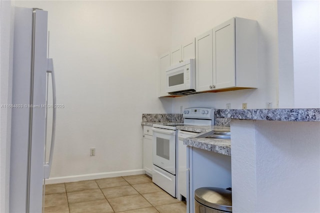 kitchen featuring white appliances, baseboards, white cabinets, light countertops, and light tile patterned flooring
