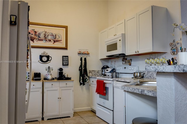 kitchen featuring white cabinets, light tile patterned floors, white appliances, and light stone counters