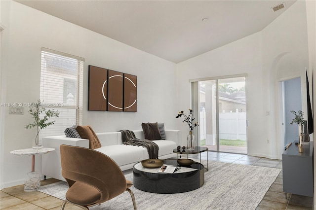living room with lofted ceiling, visible vents, baseboards, and light tile patterned floors