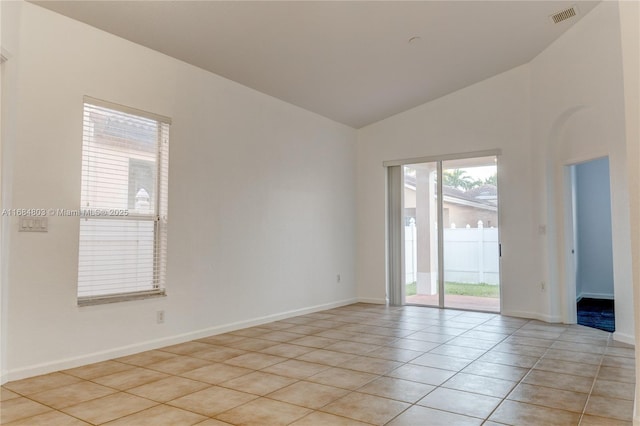 empty room featuring light tile patterned floors, baseboards, visible vents, and vaulted ceiling