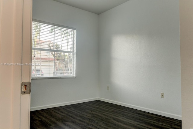 unfurnished room with baseboards and dark wood-type flooring