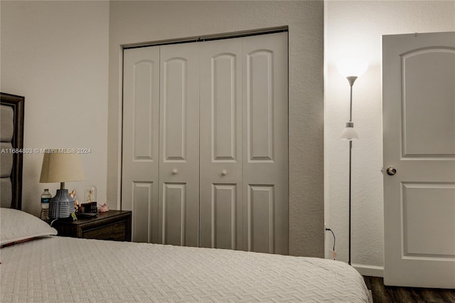 bedroom with dark hardwood / wood-style floors and a closet