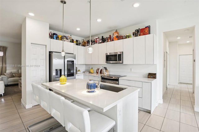 kitchen featuring white cabinets, hanging light fixtures, a breakfast bar area, appliances with stainless steel finishes, and sink