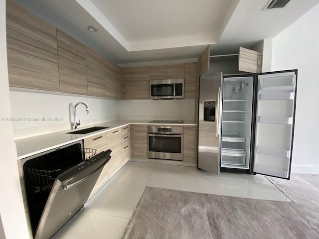 kitchen featuring stainless steel appliances, light tile patterned floors, and sink